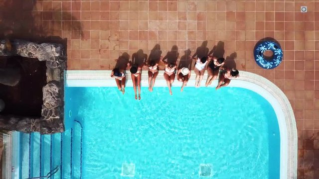 People having fun in summer at the pool with trendy coloured inflatable mattress lilos - couple of beautiful girls lay down and enjoy the sunny day together - aerial view and hotel resort concept vaca