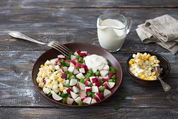 Fresh radish salad with green onions, boiled egg and sour cream on a wooden background, rustic style. Delicious homemade food