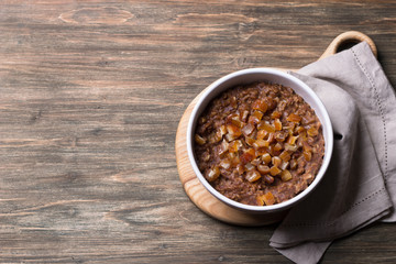 Delicious oatmeal in a white bowl, dates fruits and cocoa. healthy breakfast on a wooden background. top view