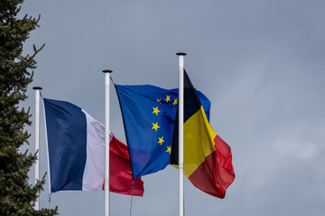 The French, Belgian and European Union's flag in a windy day
