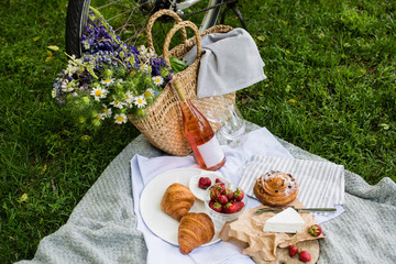 Beautiful summer picnic with strawberries, cheese and rose wine on the lawn in the city park