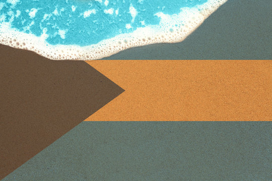 Sea wave on sandy beach with flag Bahamas. top view on surf.