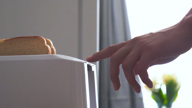 In the kitchen, a guy (girl) pulls out food from the refrigerator and prepares breakfast next to the toaster, ready-made toasters are pulled out. Concept of: Homemade Food, Comfort, Breakfast, Slow Mo