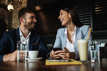 Happy couple man and woman sitting in modern cafe bar or restaurant and drinking coffee.