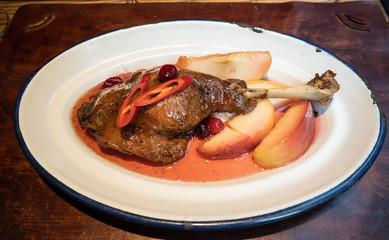 Duck leg with cherry sauce on the metal plate, baked in the oven with apples.