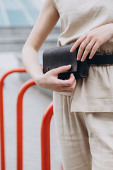 comfortable, mobile, stylish waist bag made of leather - a modern handbag for girls in two colors, posing against street , urban clothing style. Street photography