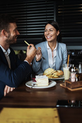 Happy couple man and woman sitting and eating in modern cafe bar or restaurant.