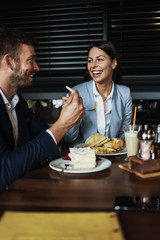 Happy couple man and woman sitting and eating in modern cafe bar or restaurant.
