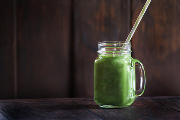 Healthy green smoothie in a jag mug on wooden background