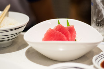 Tuna sashimi, raw fish in traditional Japanese style in white bowl.