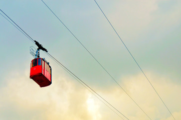 ropeway and funicular road in mountain, red cabin against a background of blue cloudy sky