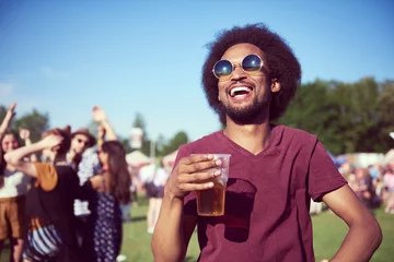 Gordijnen Happy African man drinking beer in festival © gpointstudio