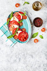 Italian caprese salad with sliced tomatoes, mozzarella, basil, olive oil