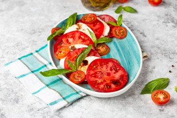 Italian caprese salad with sliced tomatoes, mozzarella, basil, olive oil