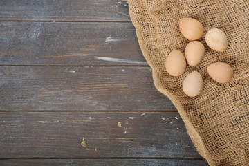 Guinea fowl eggs located on burlap on wooden dyed background. Top view.