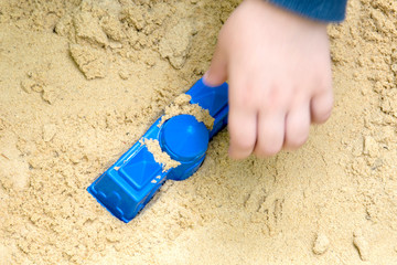 plastic sandbox toys with the hand of a playing child