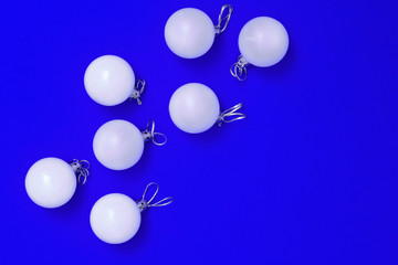 Creative New Year decoration. Composition from White Christmas balls on blue paper background. Holiday winter concept. Minimalism. Flat lay. Top View.