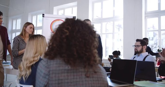 Camera moves around happy multiethnic colleagues working together, active discussion at modern office business seminar.