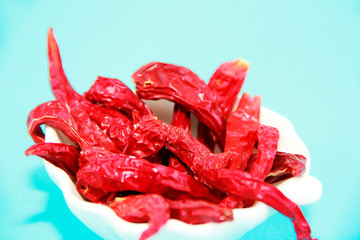 red spicy dried little pepper in white plate on a blue background