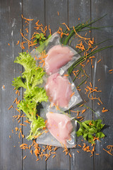 Sous Vide cooking concept. Vacuum packed ingredients arranged on wooden dyed background. Top View.