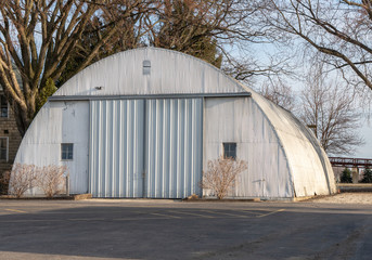 Fototapeta na wymiar Vintage quonset hut, corrugated metal building with 2 windows. Half circle round building common after WWII. Concepts of architecture, construction, history