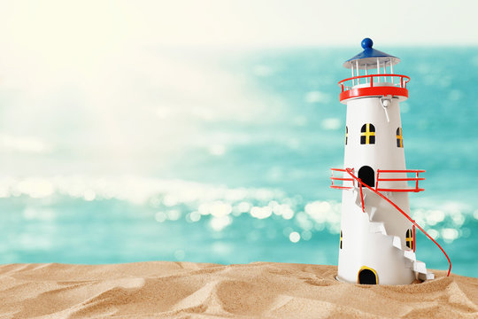 vacation and summer concept with vintage boat, starfish, lighthouse and seashells over beach sand