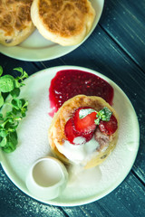 Top view. Close up, macro. Rustic breakfast. Cheese pancakes, poured with cream and decorated with strawberries.