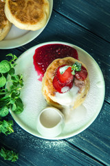 Top view. Close up. Rustic breakfast. Cheese pancakes, poured with cream and decorated with strawberries.