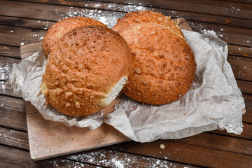 tasty bread on white paper on brown wooden board