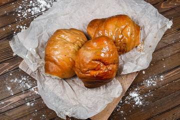 tasty bread on white paper on brown wooden board