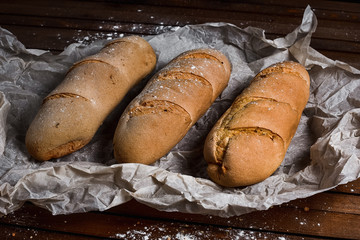 tasty bread on white paper on brown wooden board