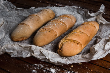 tasty bread on white paper on brown wooden board