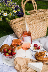 Beautiful summer picnic with strawberries, cheese and rose wine on the lawn in the city park