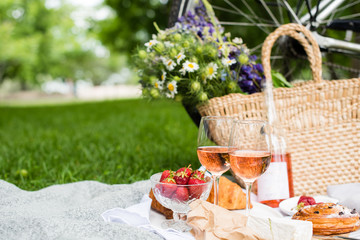 Beautiful summer picnic with strawberries, cheese and rose wine on the lawn in the city park
