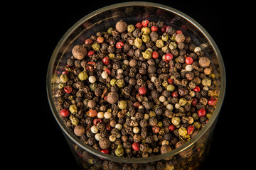 top view closeup mix of different peppercorns in deep glass