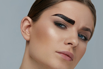 Naklejka premium Beauty makeup. Woman coloring eyebrow with brow gel tint