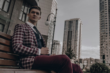 Young stylish businessman portrait, male model in full suit. Classic style concept. Success. Corporate manager posing near buildings.