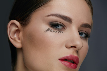 Beauty face makeup. Woman model with make-up and word on skin