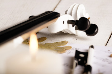 Close view of a white violin dry oak leaves musical notes and candle on wooden table