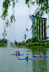 Young girls paddling on SUP board on a calm lake at city. Sup surfing group women. Awesome active training in nature.