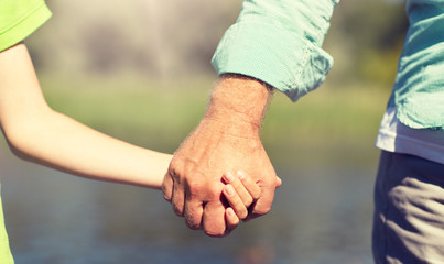 family, generation, support and people concept - senior man and child holding hands