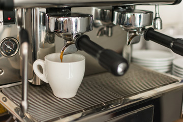 Espresso pouring from coffee machine into one cup