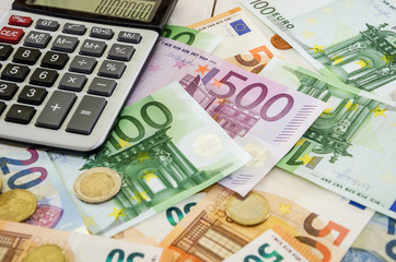 euro banknotes, coins and calculator on white table