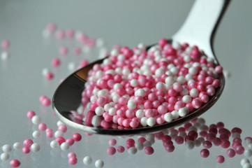 pink and white sugar pearls in a tea spoon