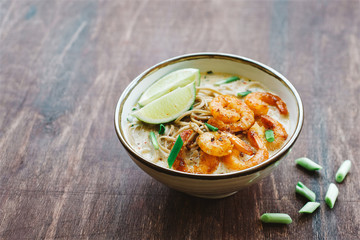 Coconut curry soup with noodles and shrimps in bowl. Asian cuisine concept