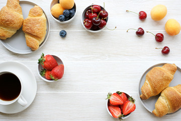 Coffee, croissants and berries for breakfast on white wooden background. Copy space
