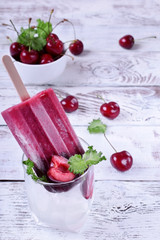 Berry popsicle with cherries against the white wooden background