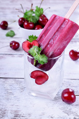 Berry popsicle with cherries against the white wooden background