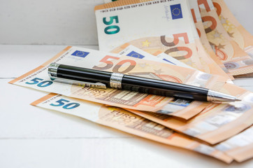 banknotes in  of 50 euros and a pen on the table. Close-up.