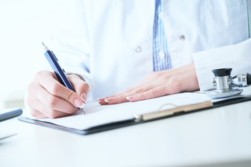 Female medicine doctor hand holding silver pen writing something on clipboard closeup.. Ward round, patient visit check, medical calculation and statistics concept.